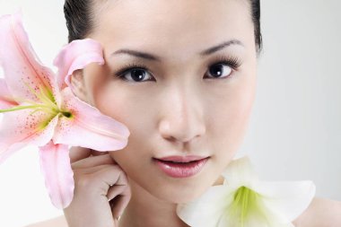 Kameraya poz verirken elinde çiçekler olan kadın.