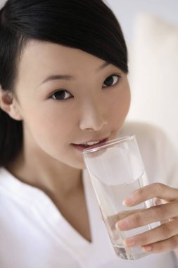 Bir bardak su içerken gülümseyen kadın.