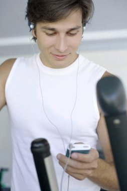 MP3 çalarını dinlerken koşu bandında egzersiz yapan adam