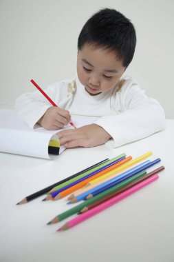 Renkli kalemle çizim yapan çocuk