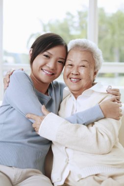 Yaşlı kadın ve kadın poz verirken sarılıyorlar.