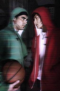 Kapüşonlu kazaklı iki adam birbirine bakıyor.