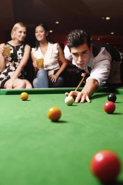 Adam bilardo oynuyor, kadın izliyor.