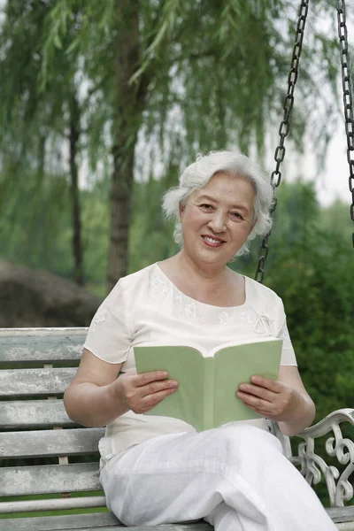 Mulher Sênior Ler Livro Enquanto Sentado Balanço — Fotografia de Stock