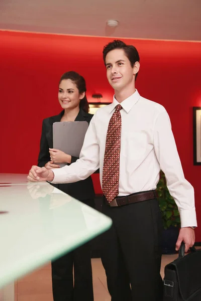 Businessman and businesswoman standing at the reception counter