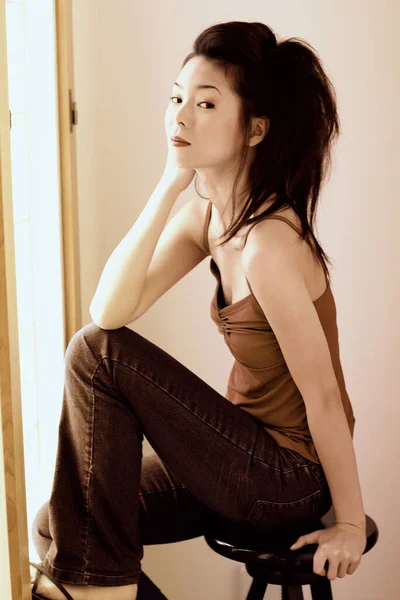Makarna Bluzlu Kot Pantolonlu Bir Kadın Taburede Oturuyor — Stok fotoğraf