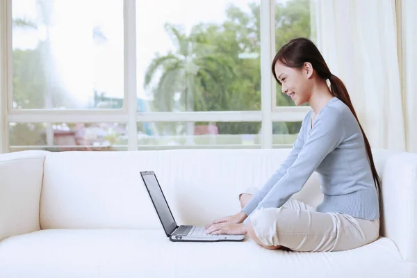 Woman sitting on the couch using laptop