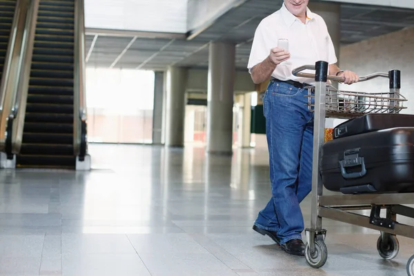 Человек Толкает Тележку Багажом Время Отправки Смс Телефону Аэропорту — стоковое фото