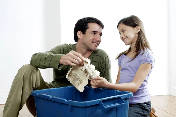 空の卵カートンをリサイクル容器に入れる男と女 — ストック写真