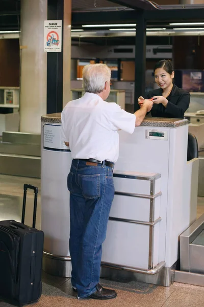 Airline check-in attendant returning businessman\'s passport at the airport check-in counter