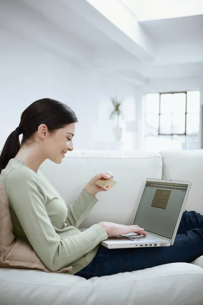 Kobieta Przeglądająca Kartę Kredytową Podczas Korzystania Laptopa — Zdjęcie stockowe