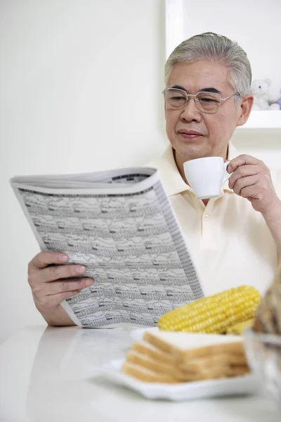 Hombre Mayor Bebiendo Café Mientras Lee Periódico —  Fotos de Stock
