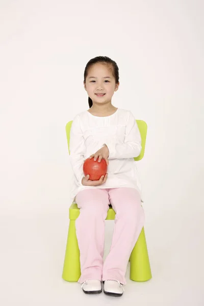 Mädchen Sitzt Auf Stuhl Und Hält Einen Roten Apfel — Stockfoto