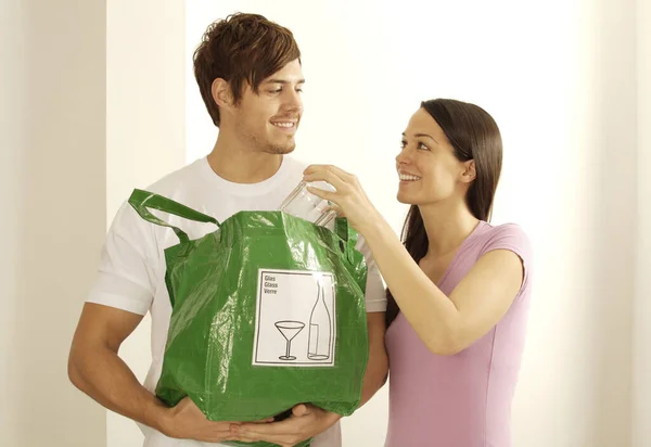 Man and woman with glass and plastic bag for recycling