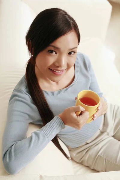 Woman enjoying a cup of tea while relaxing on the couch