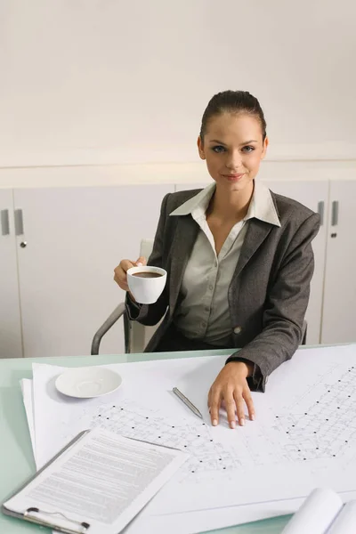 コーヒーを飲みながらテーブルの上の設計図 — ストック写真
