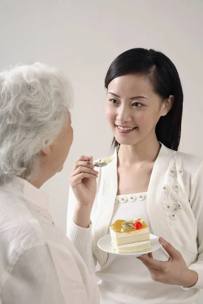 Mulher Alimentando Mulher Idosa Uma Fatia Bolo — Fotografia de Stock