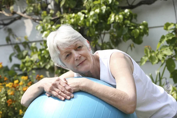 Senior woman resting on fitness ball