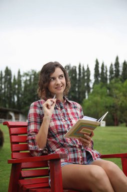 Sandalyede oturan bir kadın, günlük yazıyor.