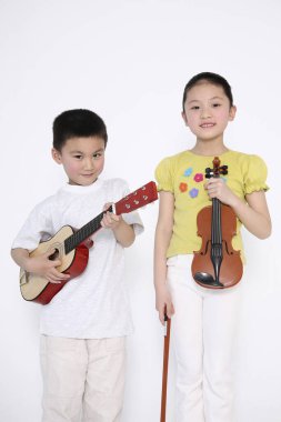 Kız kemanı tutarken oğlan gitar çalıyor.