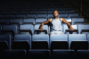 Stadyumdaki mavi koltukların arasında oturan adam