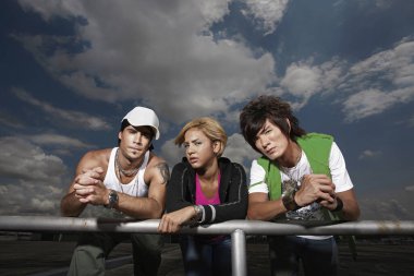 Erkekler ve kadınlar trabzanda dinleniyor, kameraya bakıyorlar.