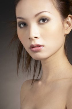 Makyajlı ve saç kesimli bir kadının stüdyo fotoğrafı.
