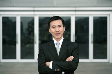 İş adamı kameraya gülümserken kollarını kavuşturuyor.