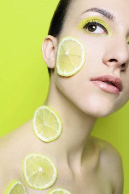Yüzünde ve boynunda limon dilimleri olan bir kadın.