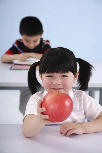 Menina Segurando Maçã Vermelha Com Menino Estudando Fundo — Fotografia de Stock