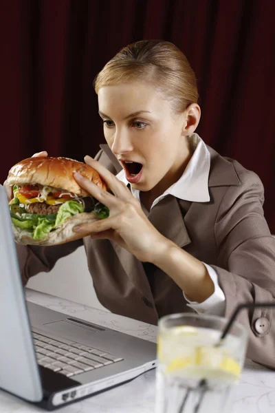 Businesswoman about to bite on a big burger