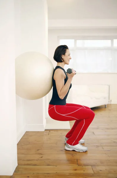 Mulher Pressionando Bola Fitness Contra Parede Levantar Halteres — Fotografia de Stock