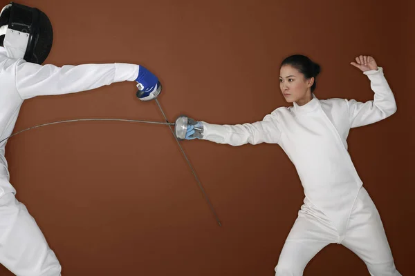 Woman with fencing foil attacking her opponent