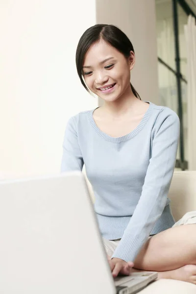 Woman sitting on the couch using laptop