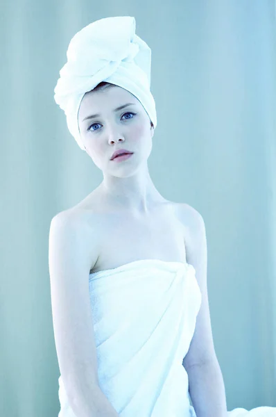 A woman with her hair and body wrapped up in towel looking at the camera