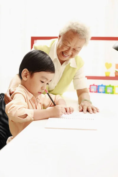 Starsza Kobieta Pomaga Chłopcu Odrabianiu Lekcji — Zdjęcie stockowe