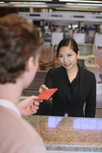 Airline check-in attendant returning man's passport at the airport check-in counter