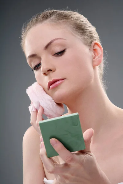 Woman applying powder with powder puff