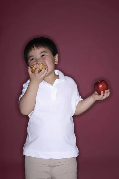 Niño Sosteniendo Donut Manzana Cada Mano Comiendo Donut —  Fotos de Stock