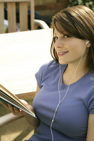 十代の女の子は音楽を聞いている間に本を読んで ストック写真