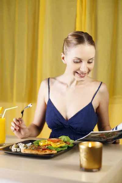 Vrouw Lezen Tijdschrift Terwijl Genieten Van Haar Pizza Salade Schotel Stockfoto