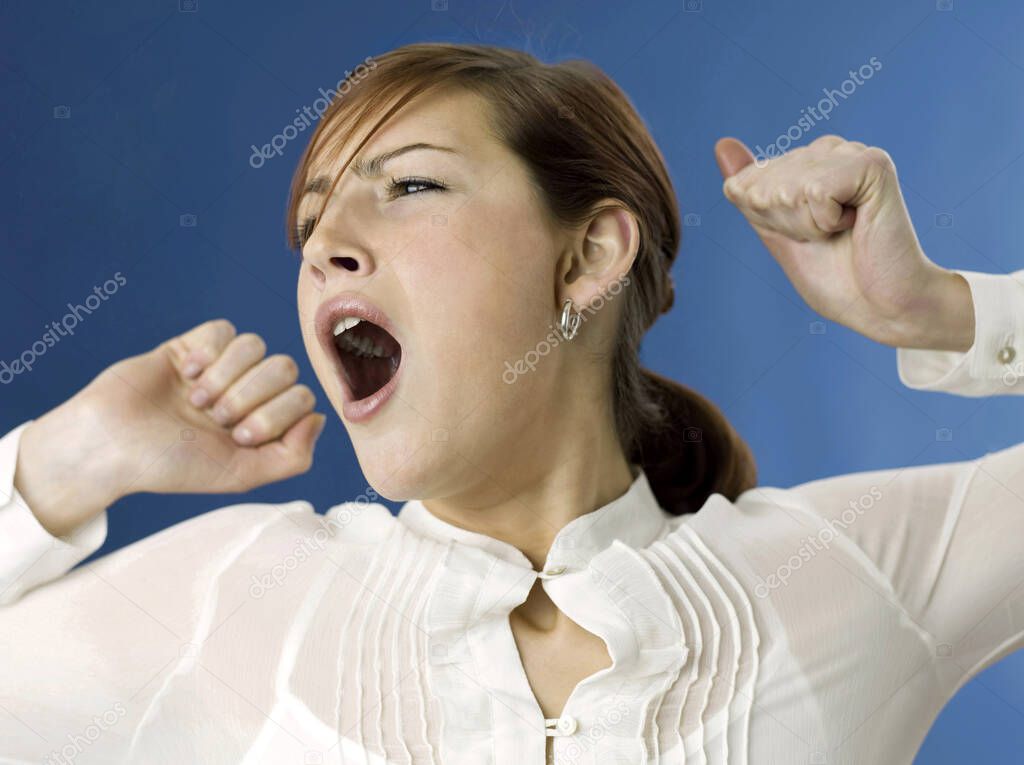 Woman yawning on blue background 