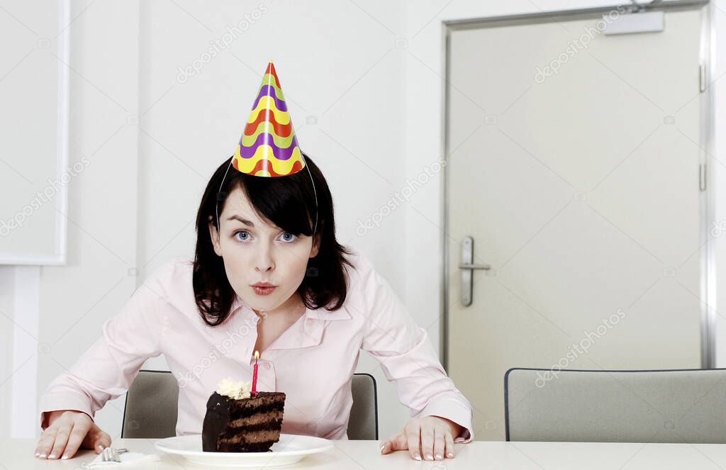 Businesswoman blowing the candle on her birthday cake