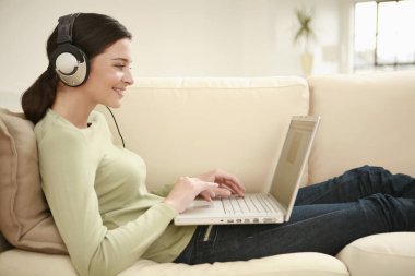 Kulaklıklı kadın dizüstü bilgisayar kullanıyor.