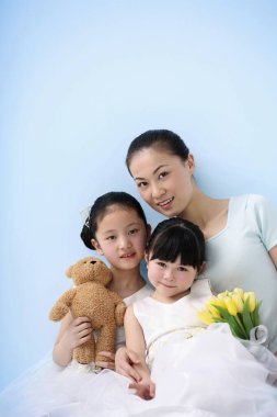 Kadın ve iki kız kameraya gülümsüyor.