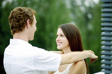 Genç çift birbirine bakarken gülümsüyor.