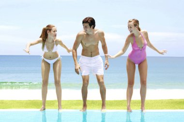 Man and two women at the swimming pool clipart
