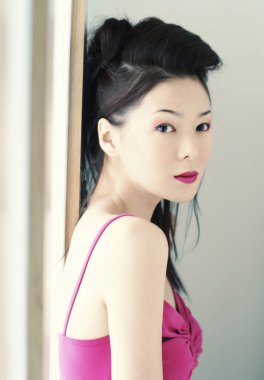 Kırmızı spagetti bluzlu bir kadın pencerenin önünde duruyor.