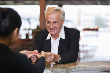 Havaalanı kayıt gişesinde iş adamının pasaportunu iade eden havayolu kayıt görevlisi.