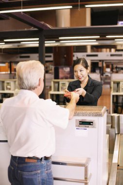 Havaalanı kayıt gişesinde iş adamının pasaportunu iade eden havayolu kayıt görevlisi.